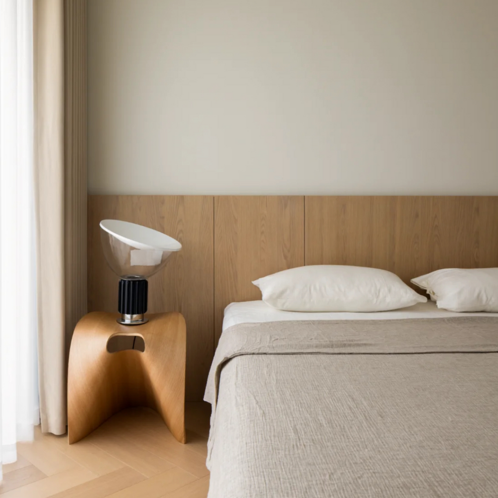 Airy bedroom with lamp on wooden side table