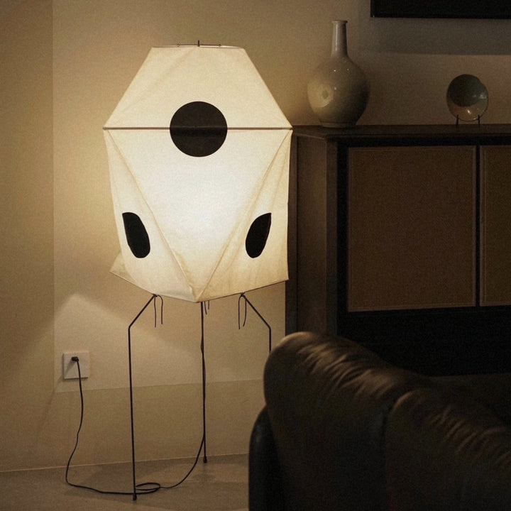 architectural floor lamp with structured paper shade positioned next to seating.