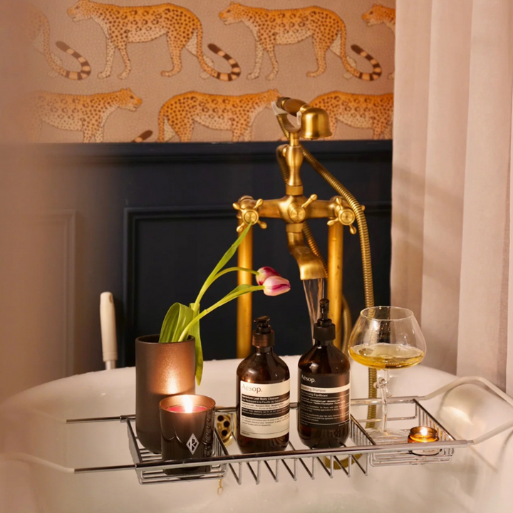 Luxury bathroom setup with a modern wine glass, candles, and toiletries on a bath tray, enhancing the relaxing ambiance.