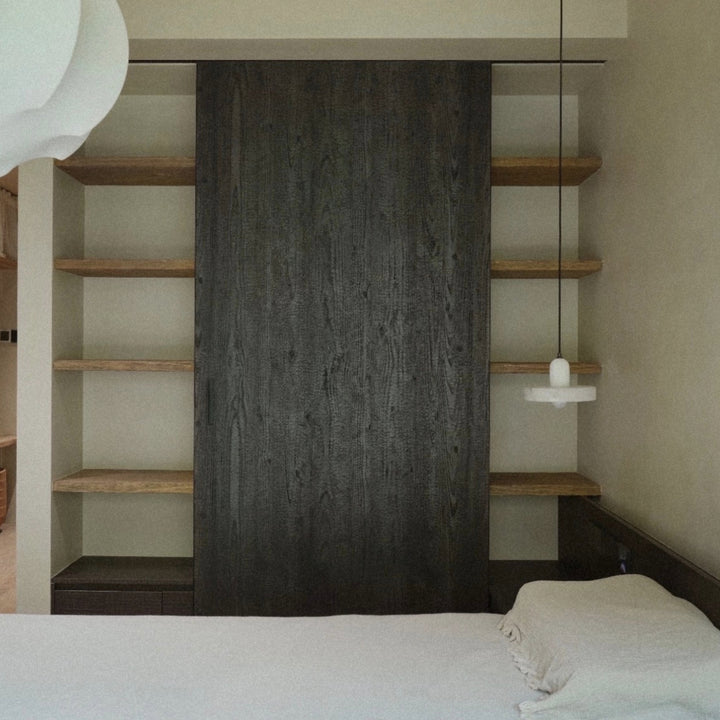 pendant light used as bedroom lighting beside a bed and open shelving.