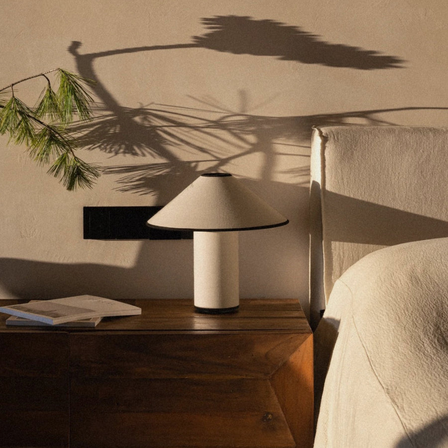 bedroom table lamp on a bedside surface with natural light and shadows.