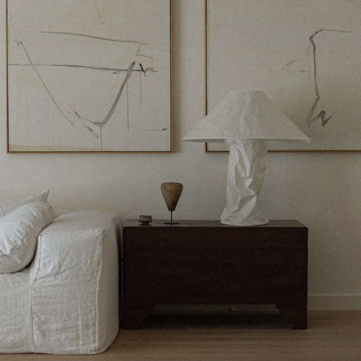 bedside table lamp with a sculptural base set beside a neatly styled bed.
