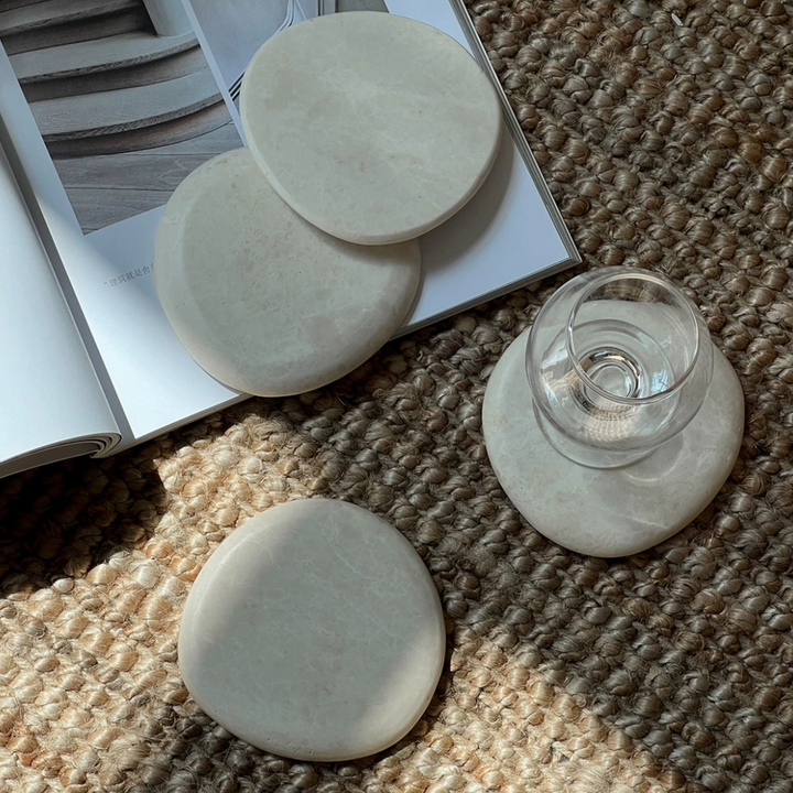 Beige marble coasters on a textured rug, perfect for adding a subtle elegance to any casual setting.