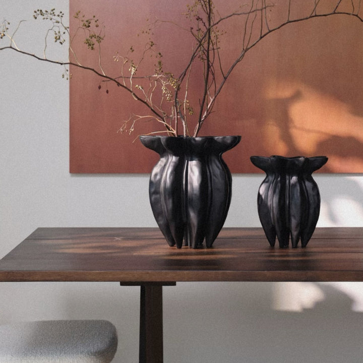 black ceramic vase used as a tabletop accent with dried stems in a bright interior.