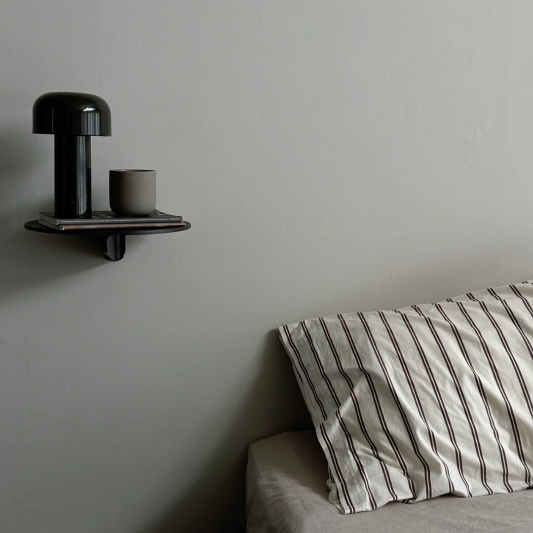 A polished black mushroom lamp sitting elegantly on a marble coffee table with design books and red accents.