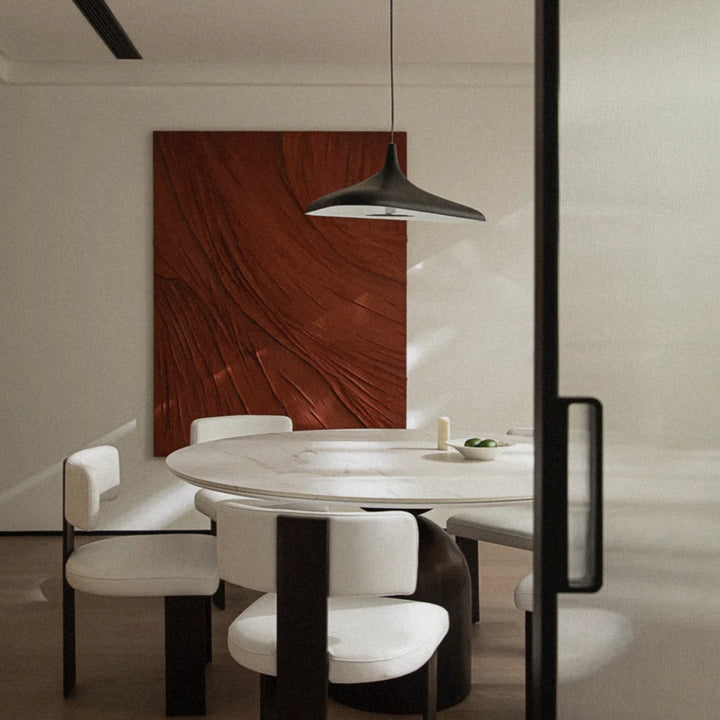 black modern pendant light suspended above a round dining table creating a focal point in a contemporary interior.