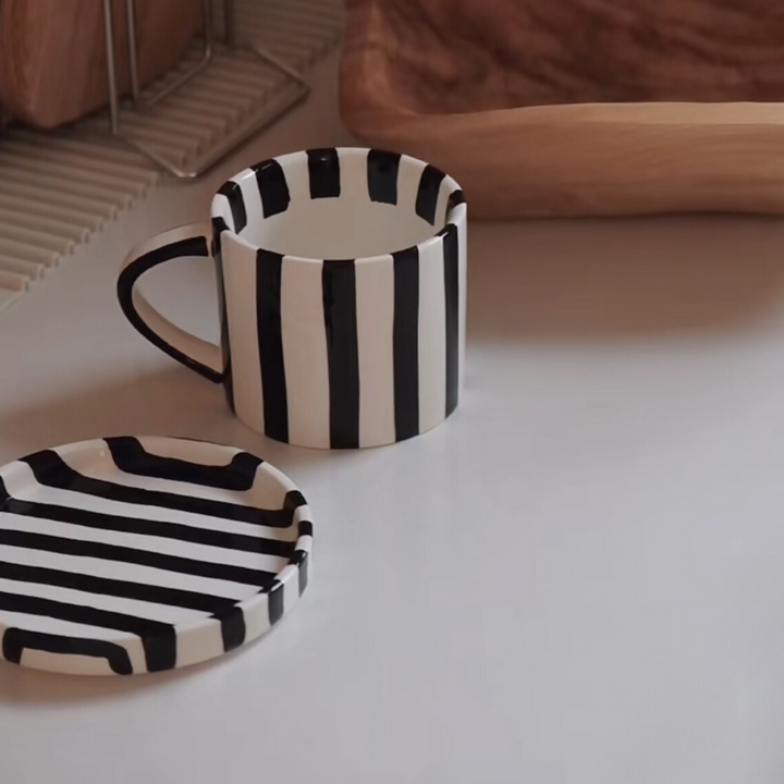 Elegant black and white striped ceramic mug on a kitchen counter, reflecting simple sophistication.