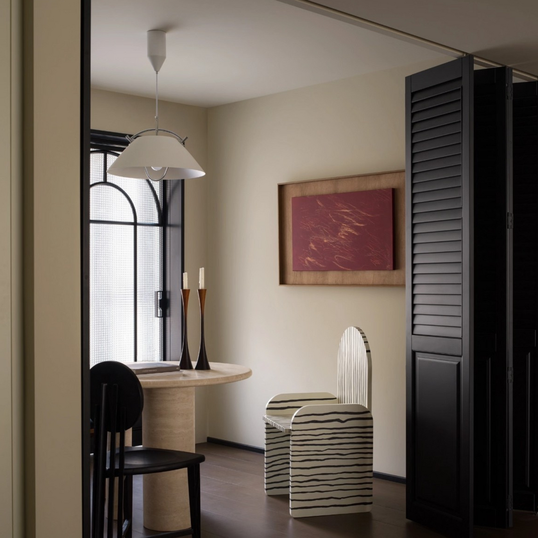 Two-tone black and walnut candle holders placed near books and ceramics in a neutral organic modern setting.