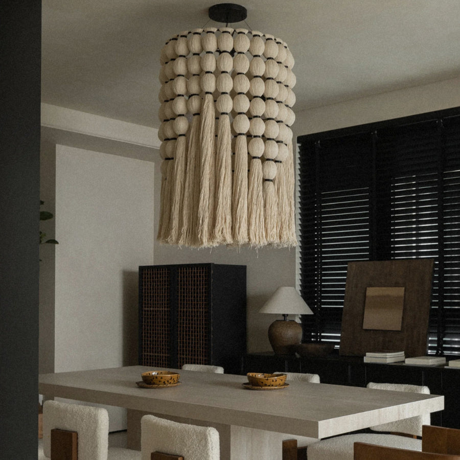 boho cotton fringe pendant light suspended above a dining table in a modern dining room.
