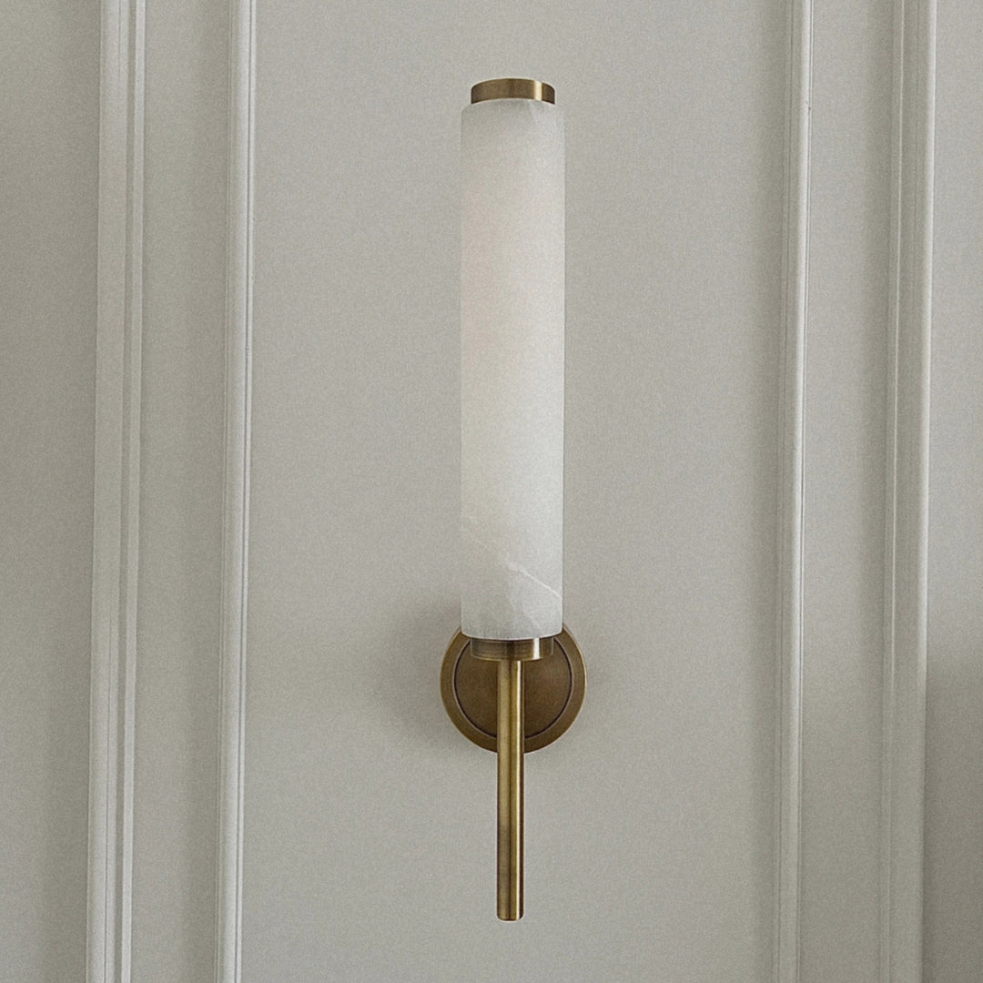 brass and marble wall sconce mounted on a wall creating soft ambient lighting in a modern interior.