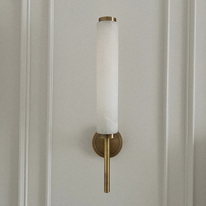 brass and marble wall sconce mounted on a wall creating soft ambient lighting in a modern interior.