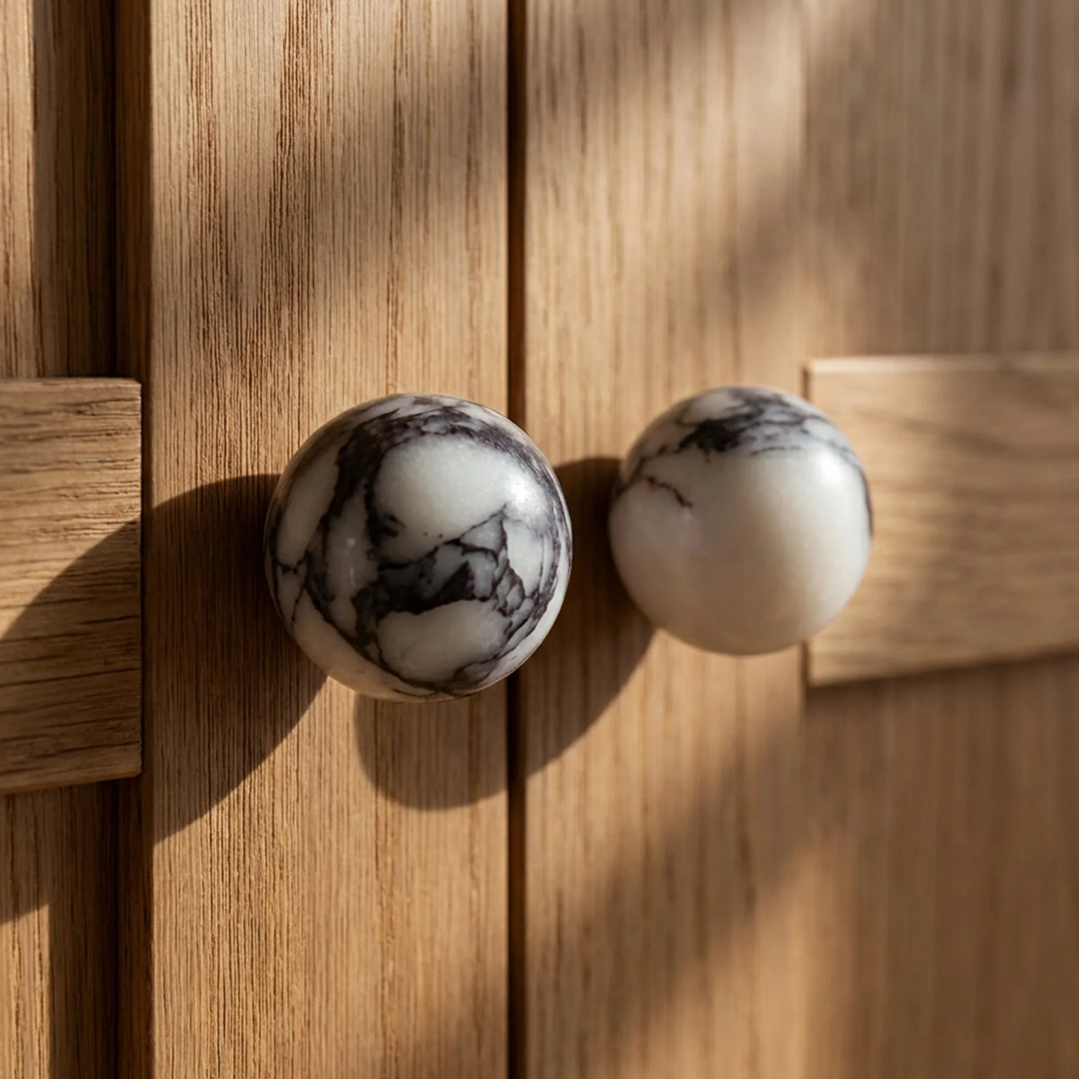 Bulgari marble stone cabinet knobs on light oak wardrobe doors in a neutral bedroom.