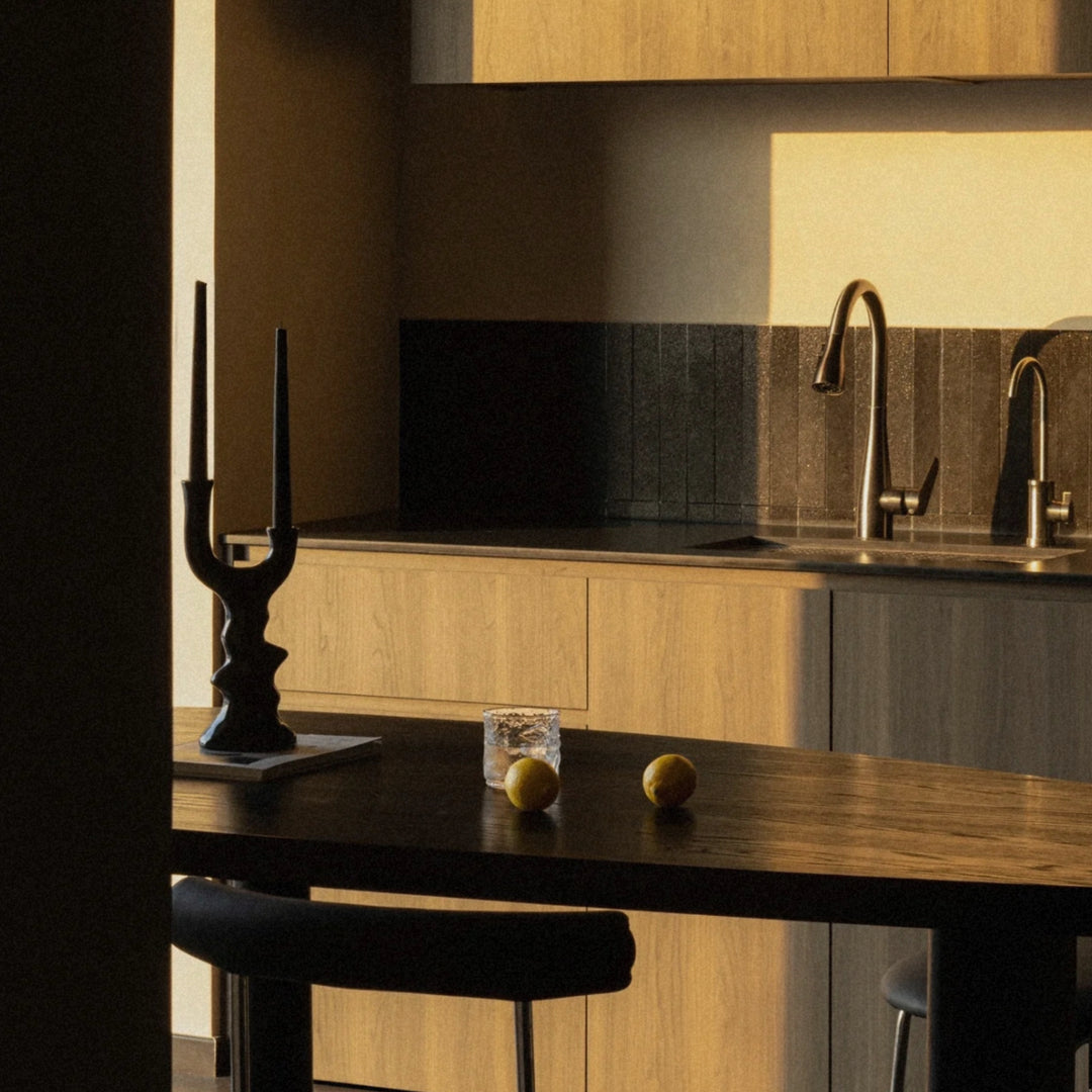 ceramic candle holder placed on a kitchen counter beside a wooden bar table.