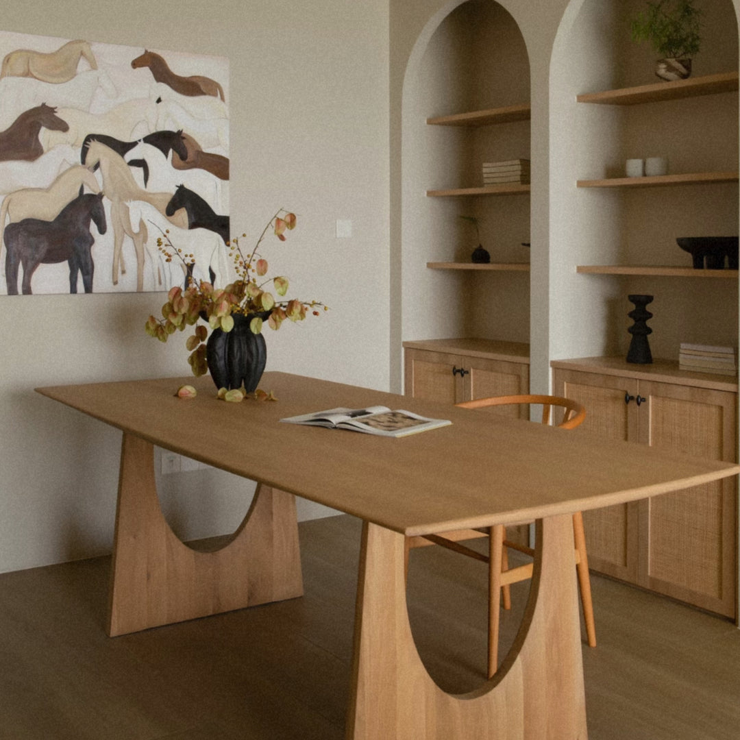on a dining table stands a ceramic vase filled with dried branches in a warm interior.