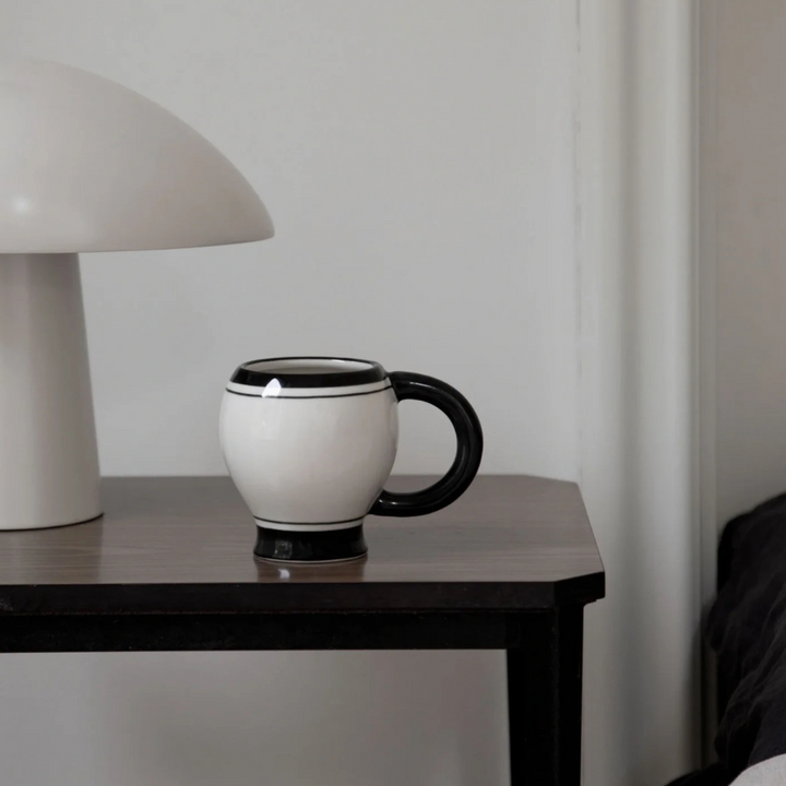 Large coffee mug on a modern table with minimalist design and contrasting black and white accents.