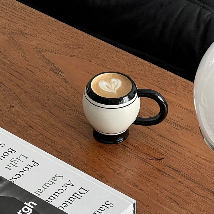 Coffee mug with latte art placed on a wooden table with a minimalist design.