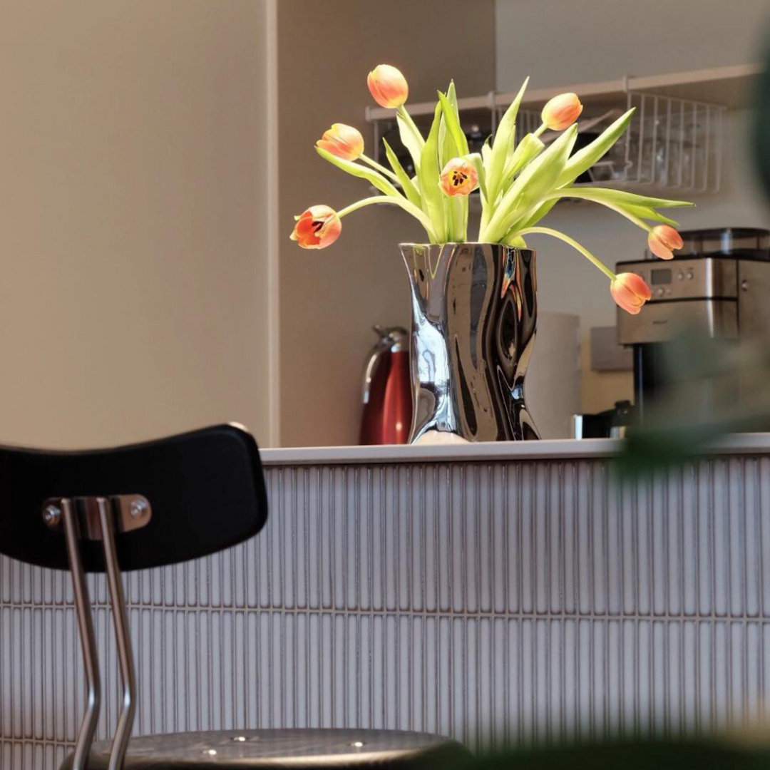 Contemporary metallic flower vase with tulips, styled on a modern bar counter for a sophisticated touch.