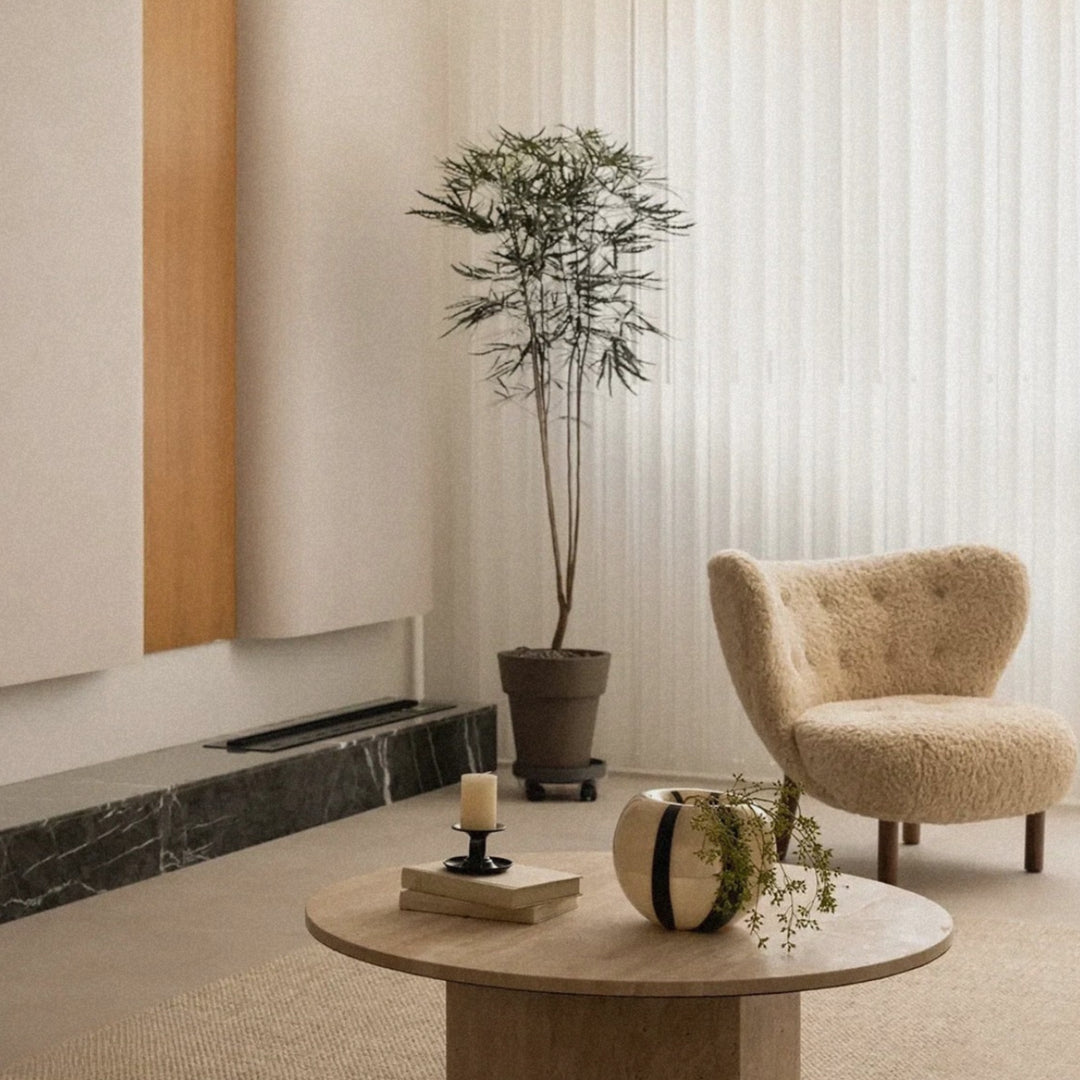 on a round table in a bright living space stands a contemporary glass vase with a bold striped pattern.