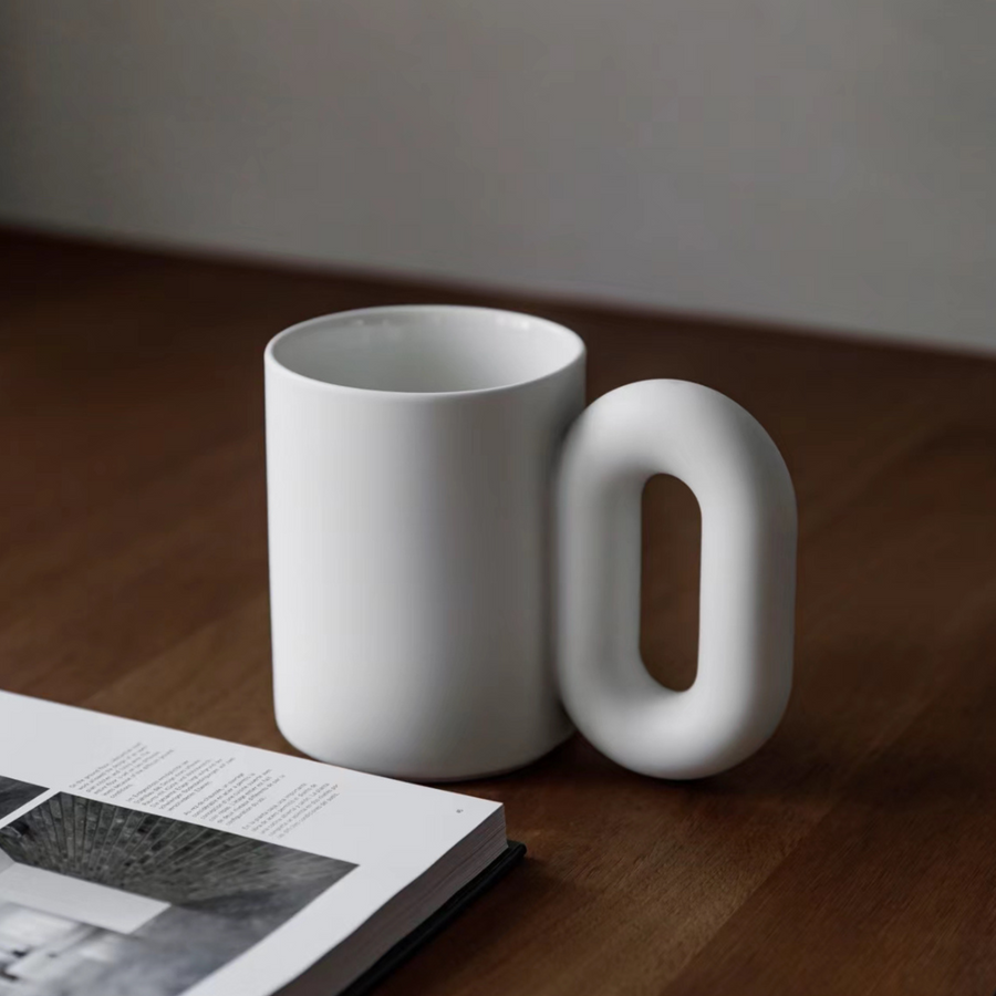 This large ceramic mug with a bold handle design is a standout piece on a contemporary desk.