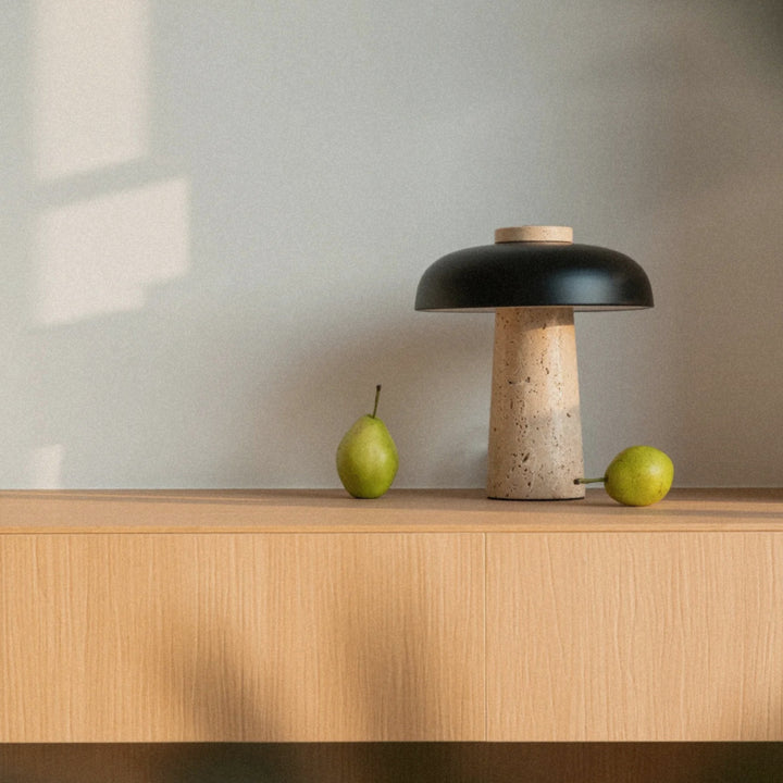 contemporary stone lamp set on a cabinet surface beside simple decorative objects.