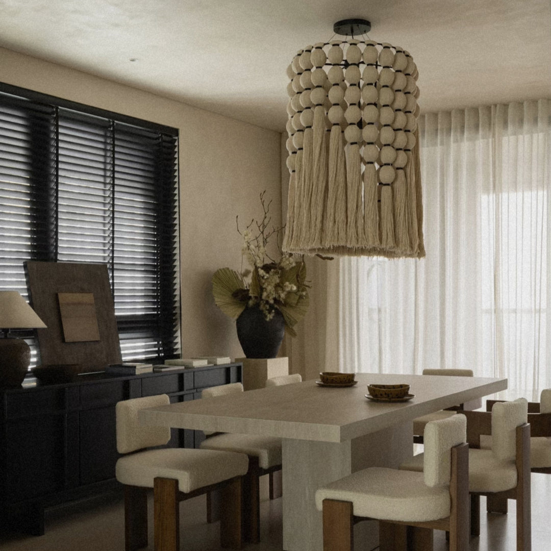 cotton thread bohemian pendant light hanging above a dining table in a bright dining room.