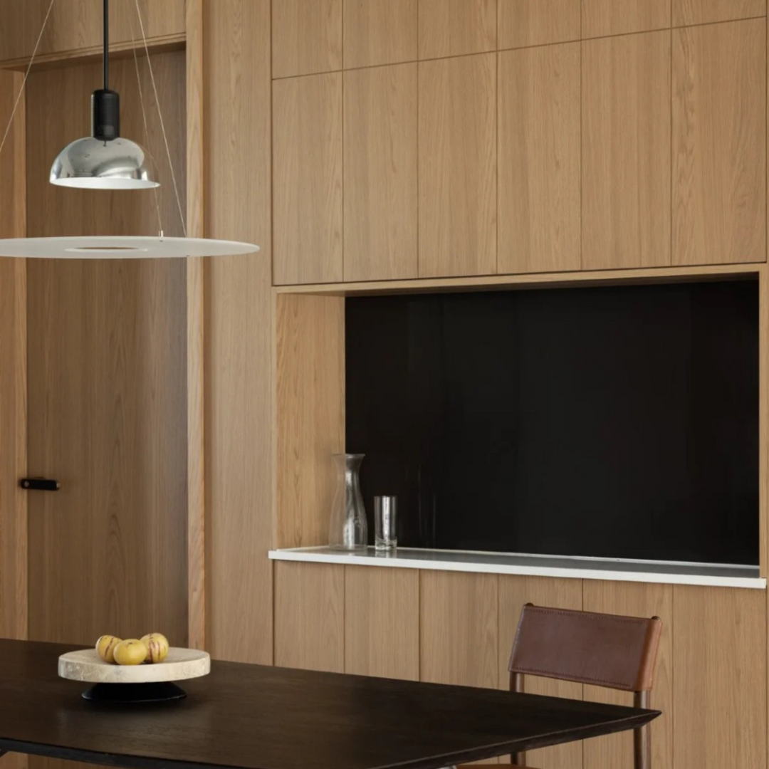 Cozy modern kitchen with chrome pendant light, wood cabinetry, and small dining table