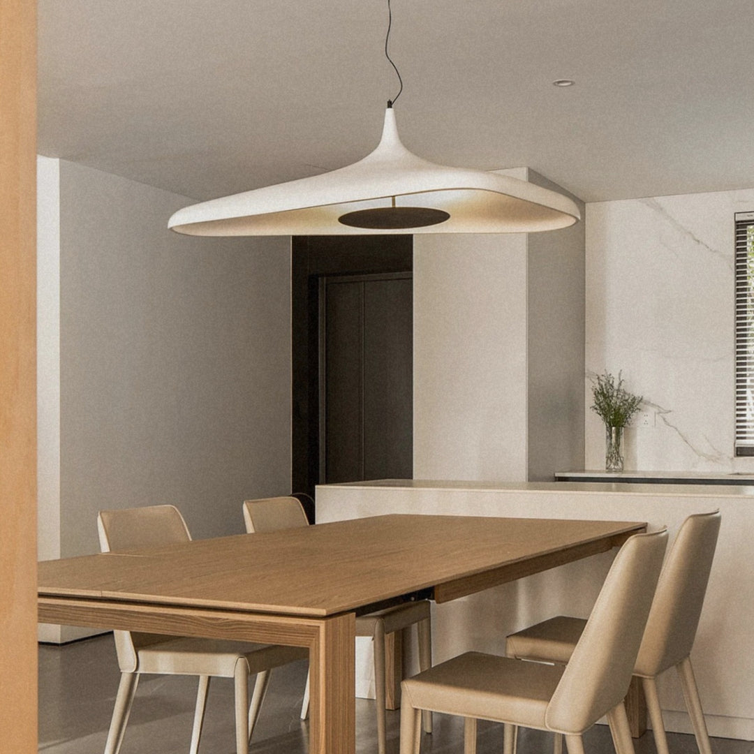 cream modern pendant light suspended above a wooden dining table in a calm japandi inspired dining space.