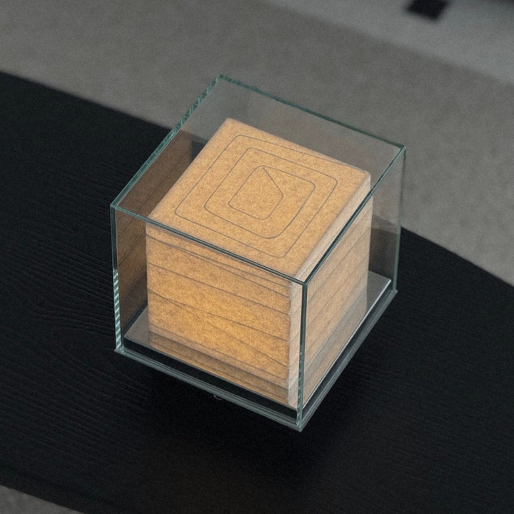 cube table lamp in glass housing set on a table in a minimal interior.