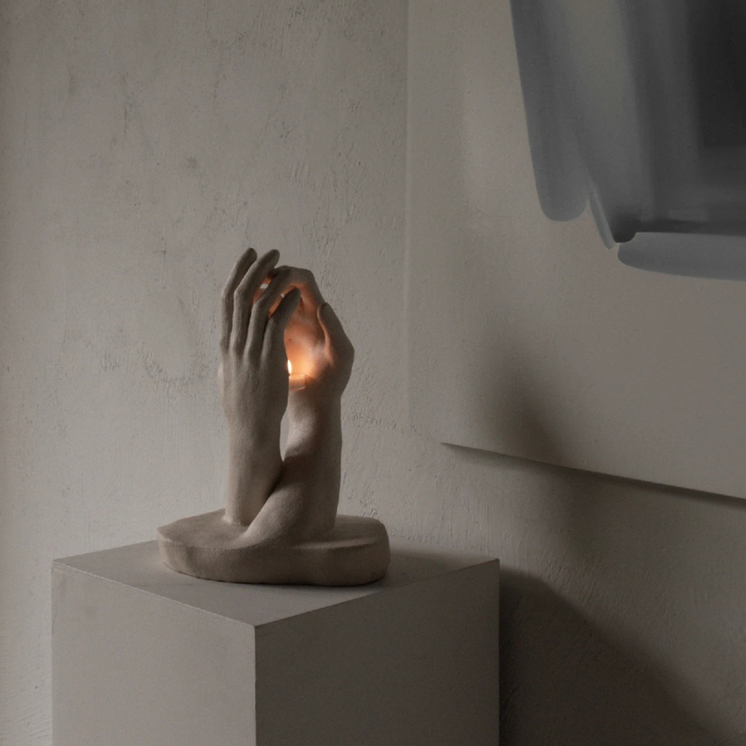 Sculptural candle holder glowing softly on minimalist pedestal