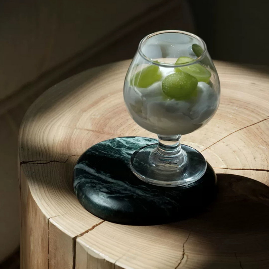 Dark green marble coaster under a glass of lime water, blending elegance with practicality.