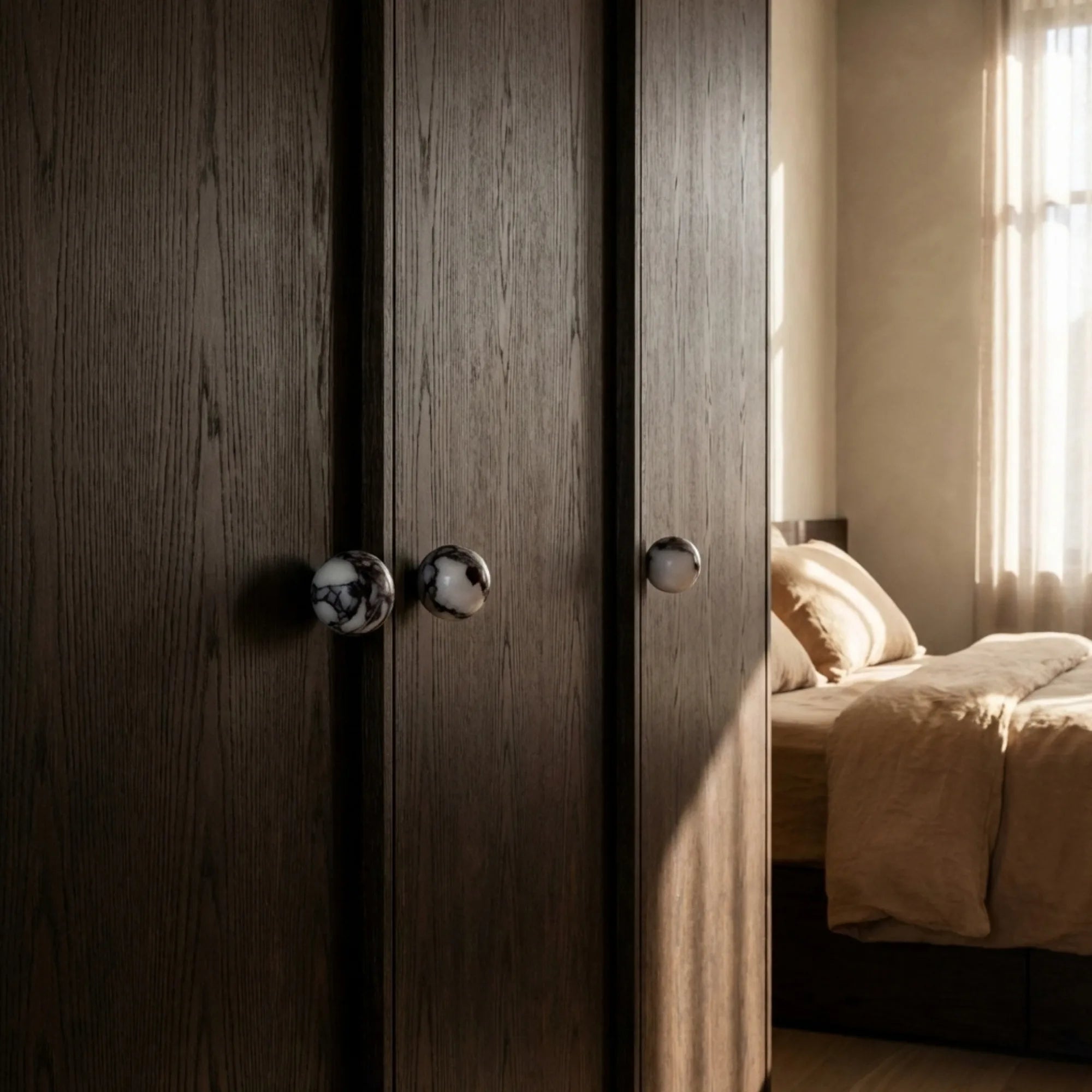 dark wood wardrobe in a bedroom fitted with bulgari stone cupboard knobs.