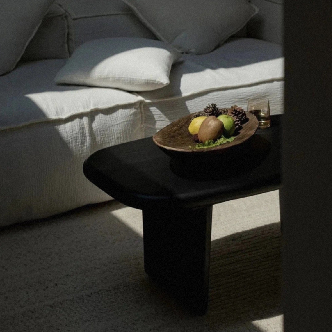 decorative fruit bowl in wood placed on a coffee table with soft shadows.