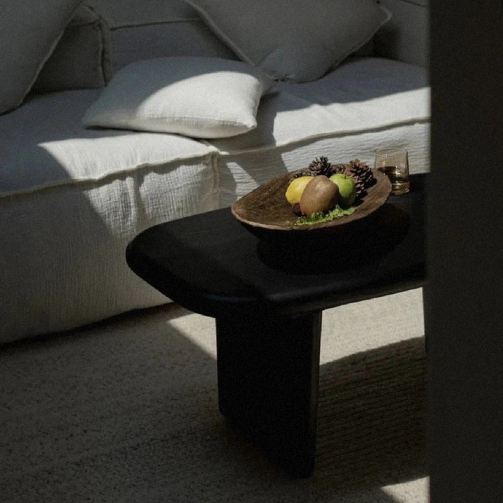 decorative fruit bowl in wood placed on a coffee table with soft shadows.