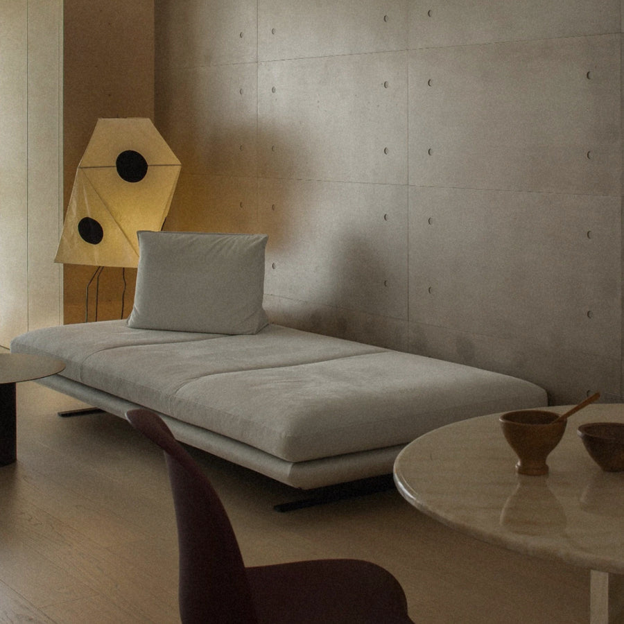designer floor light with a paper shade placed beside a lounge chair in a minimal space.