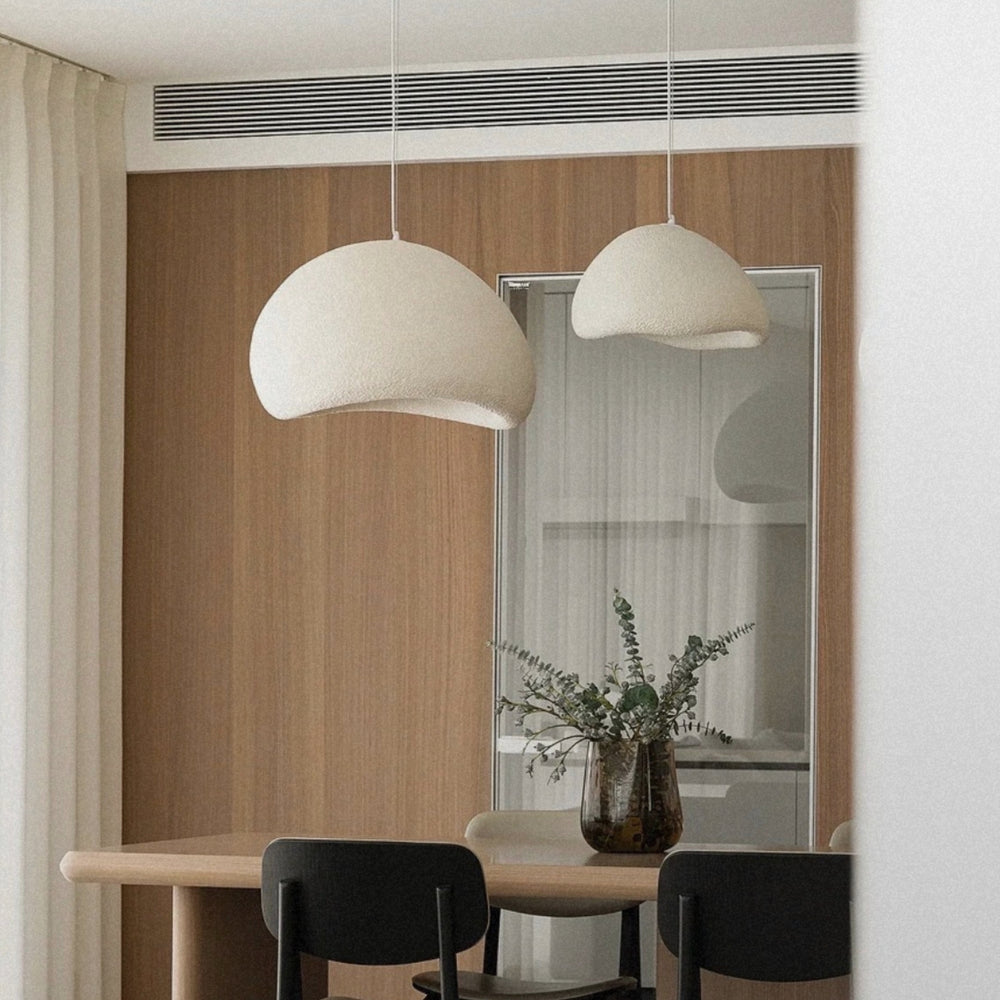 pendant light hanging low above a dining table in a minimal setting.