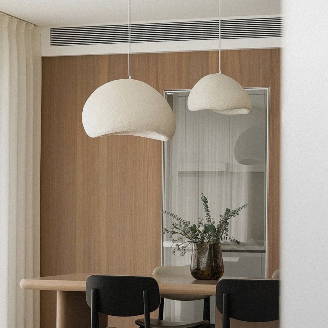 pendant light hanging low above a dining table in a minimal setting.