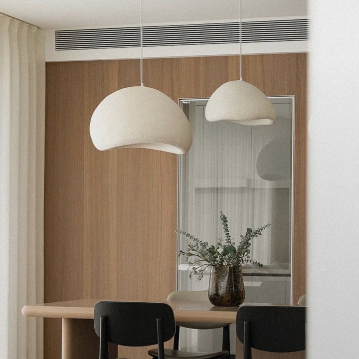 pendant light hanging low above a dining table in a minimal setting.