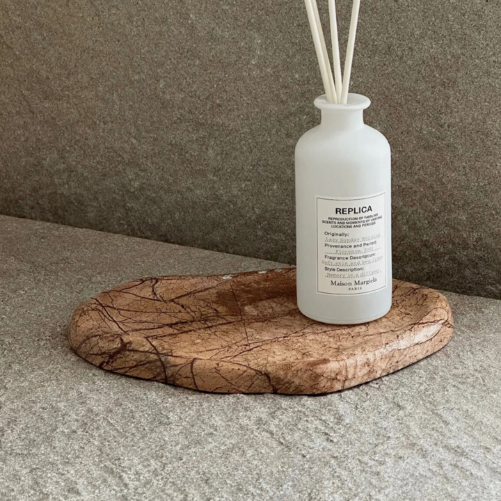 Earth-toned marble tray holding a diffuser, showcasing modern minimalism in home decor.