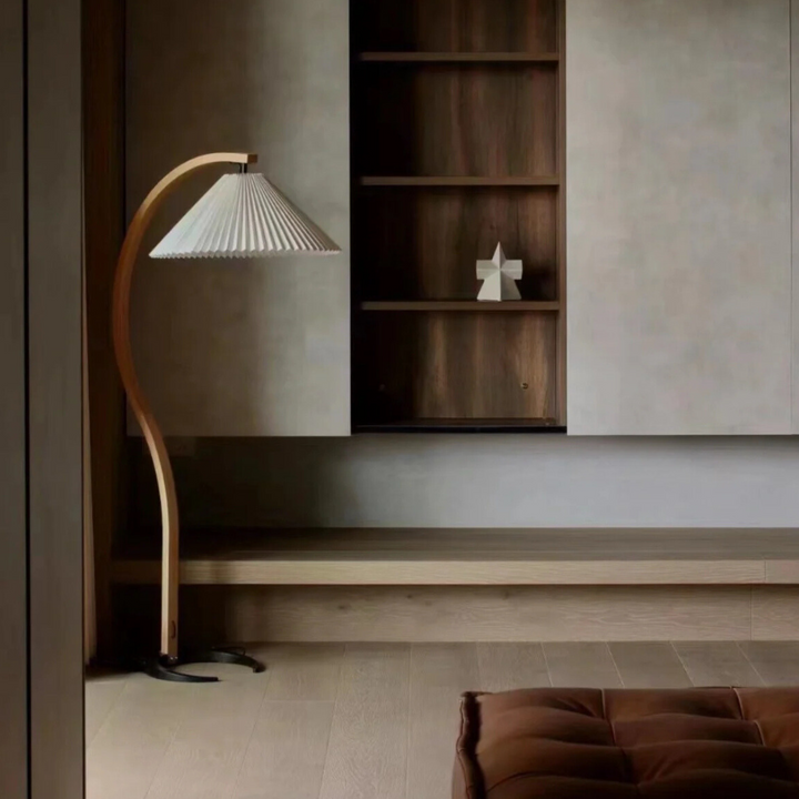 Elegant floor lamp in a corner setup beside a minimalist shelving unit in a daylight-filled room.