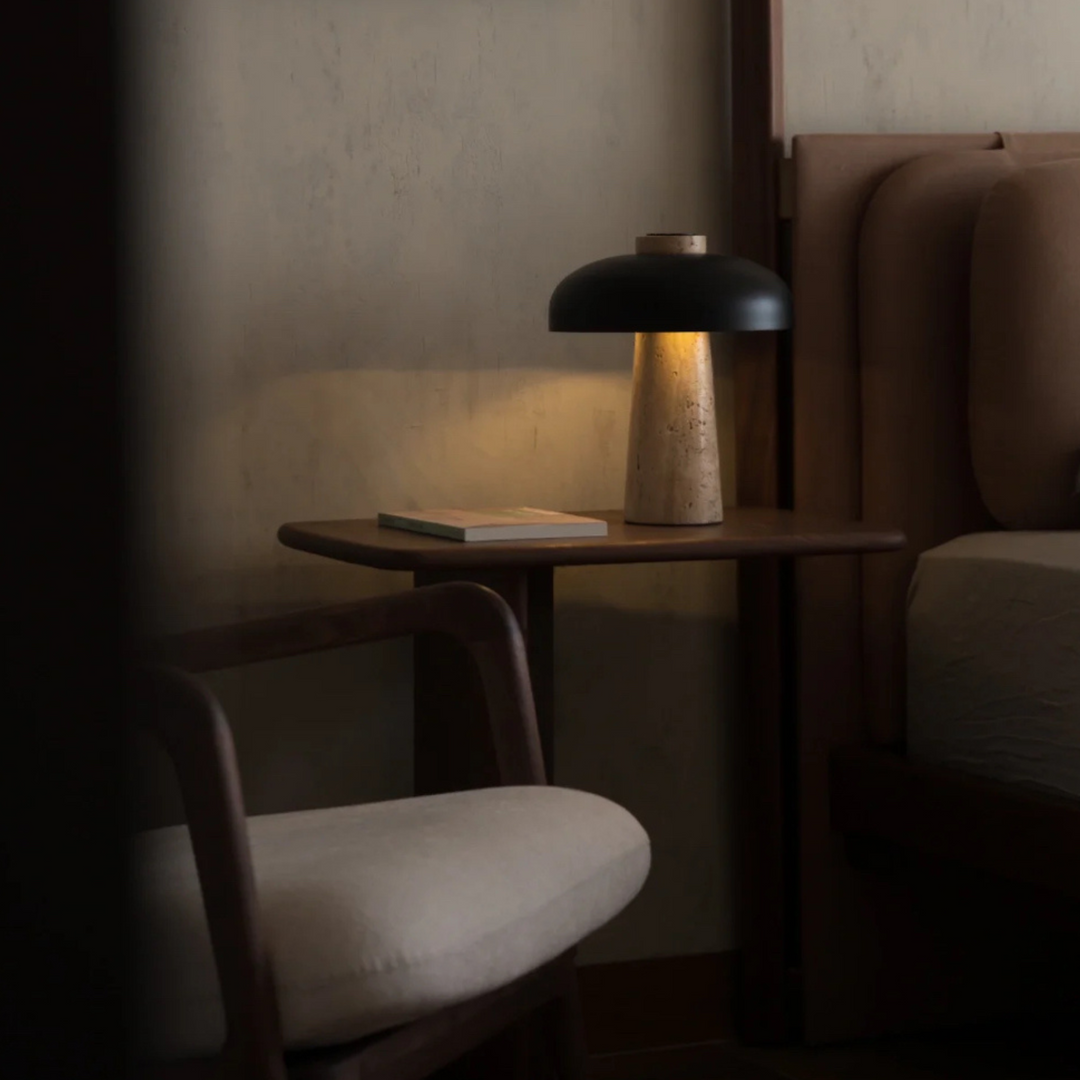 Elegant travertine table lamp in a minimalist bedroom setting, casting a soft glow.