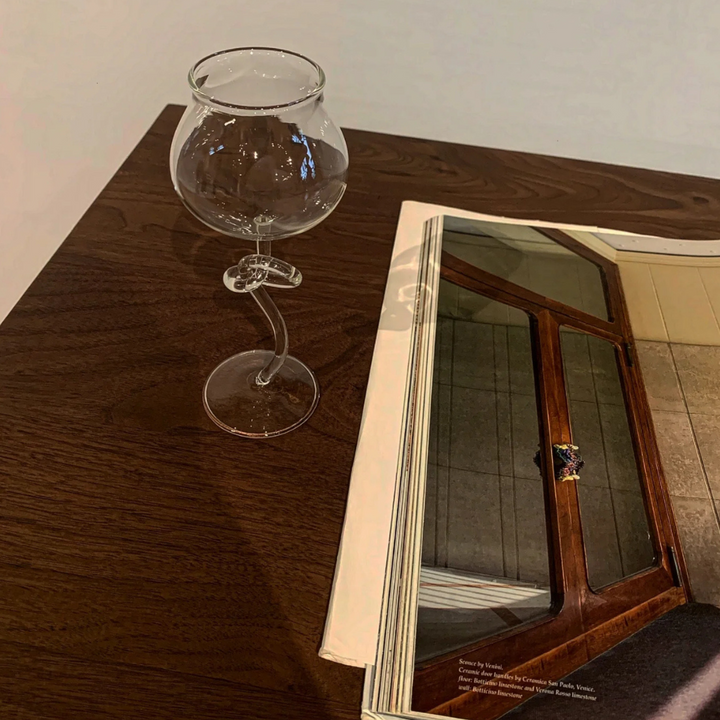 Elegant modern wine glass placed on a wooden table, creating a sophisticated vibe for a wine night setup.