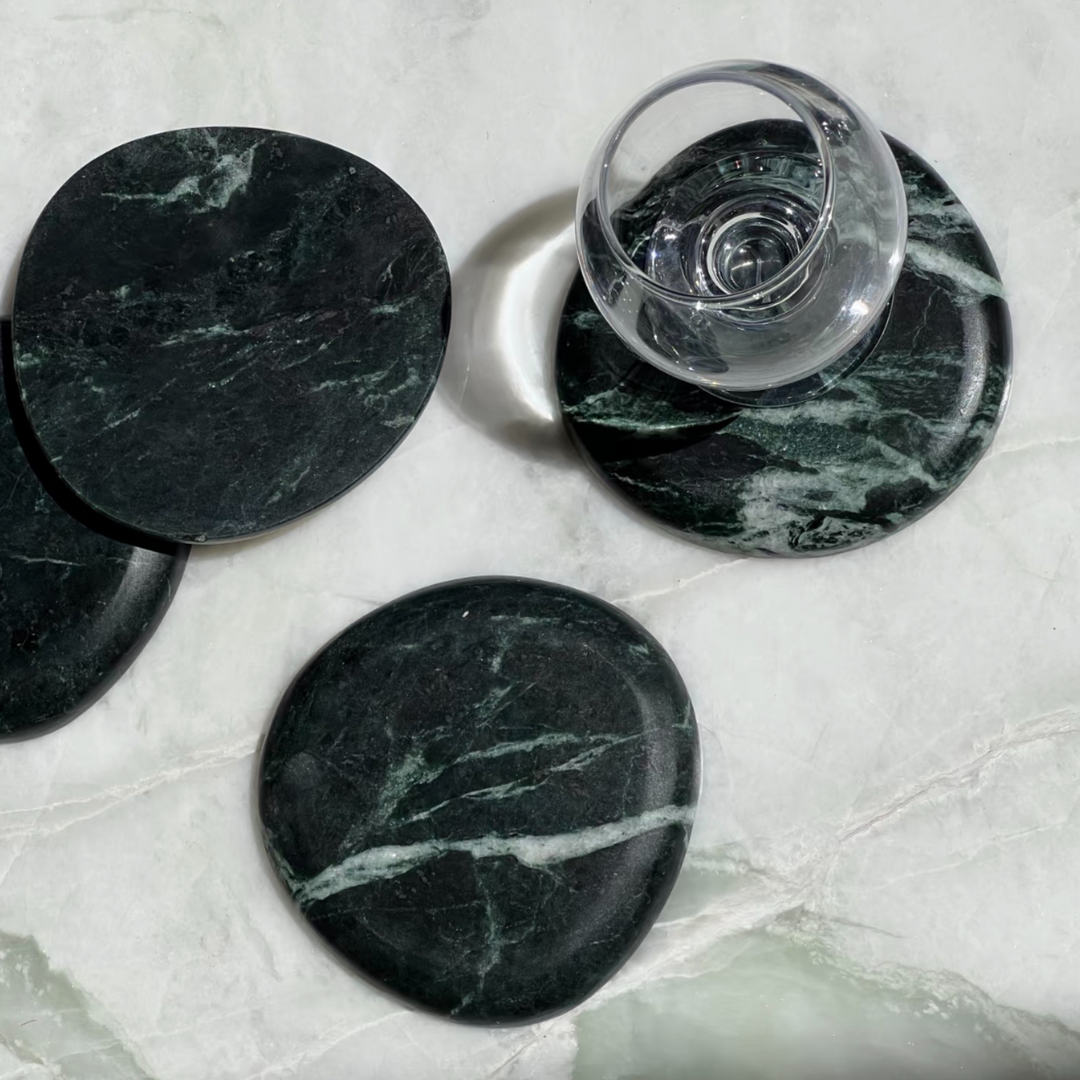 Forest green marble coasters on a polished marble table, representing timeless design and luxury.