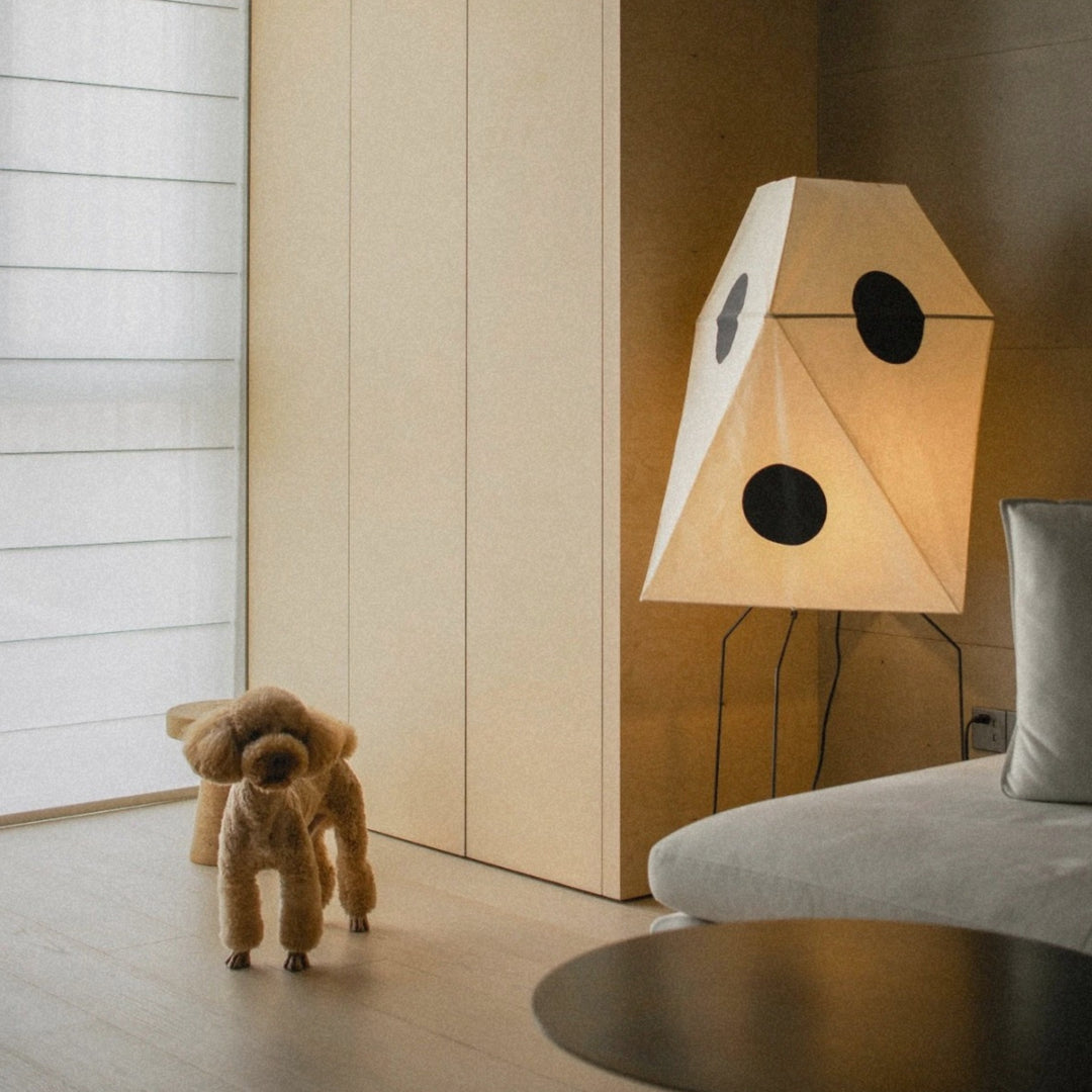 geometric paper floor lamp standing near a wall adding soft ambient lighting to the room.