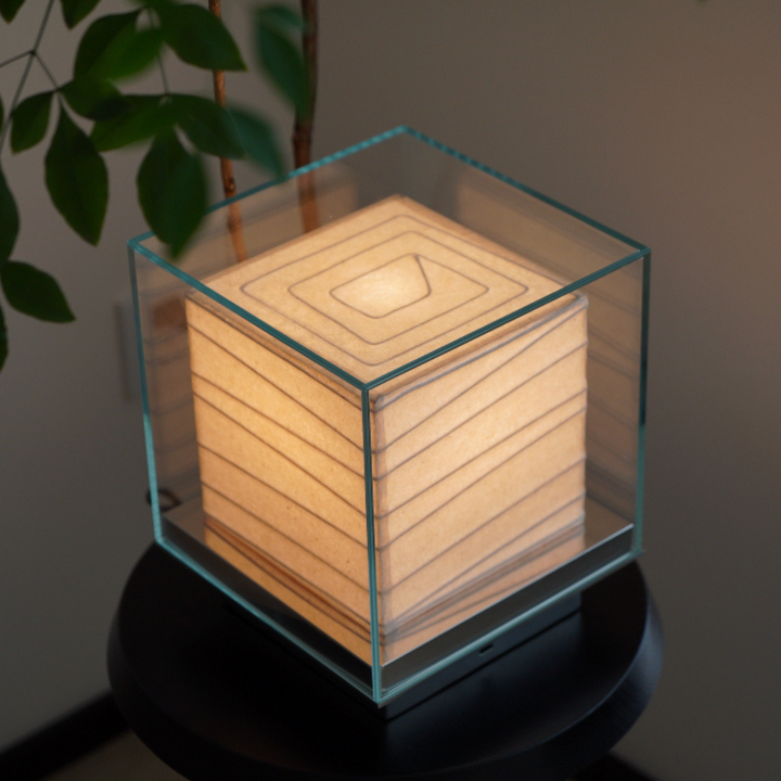 Close-up of sculptural table lamp with glass frame and soft glow