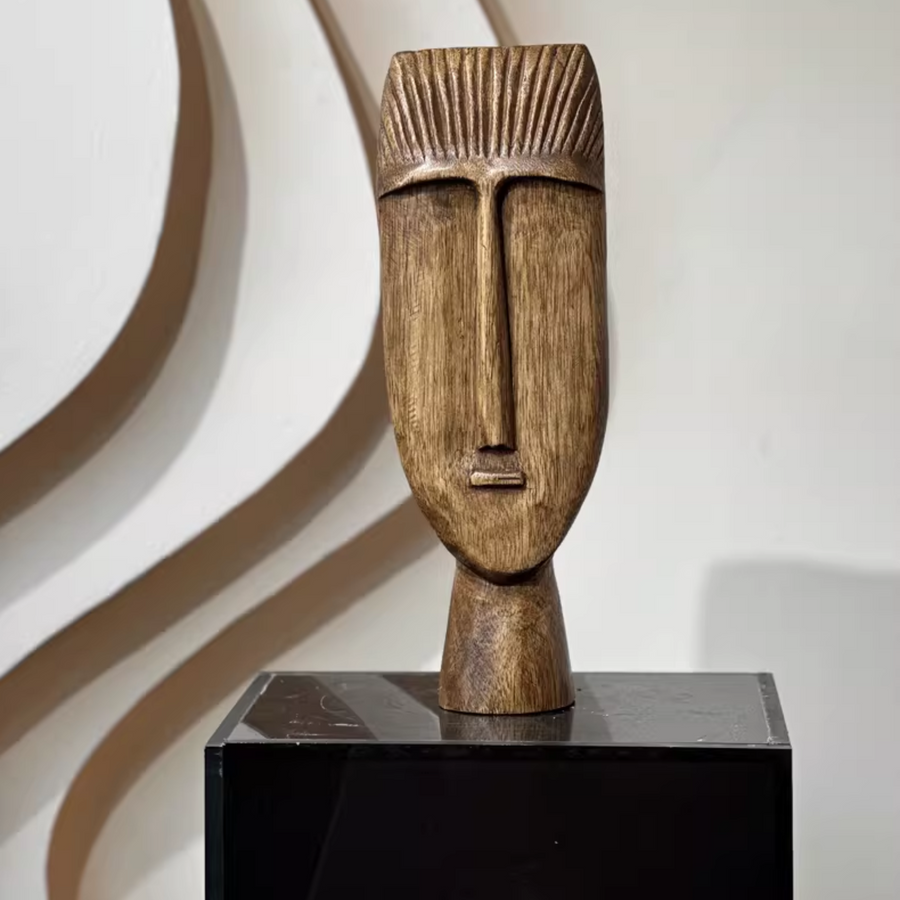 Handcrafted wooden sculpture with elongated face on a black pedestal