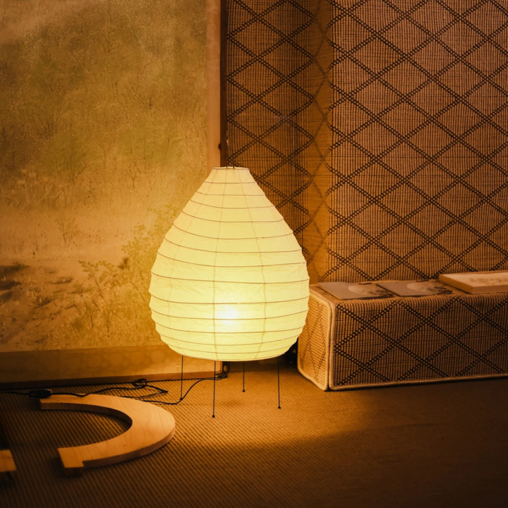 Japandi-style floor lamp softly glowing beside a warm-toned wall and neutral decor in a minimalist bedroom.