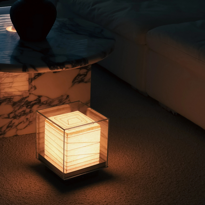 Japandi table lamp glowing beside marble coffee table in evening setting