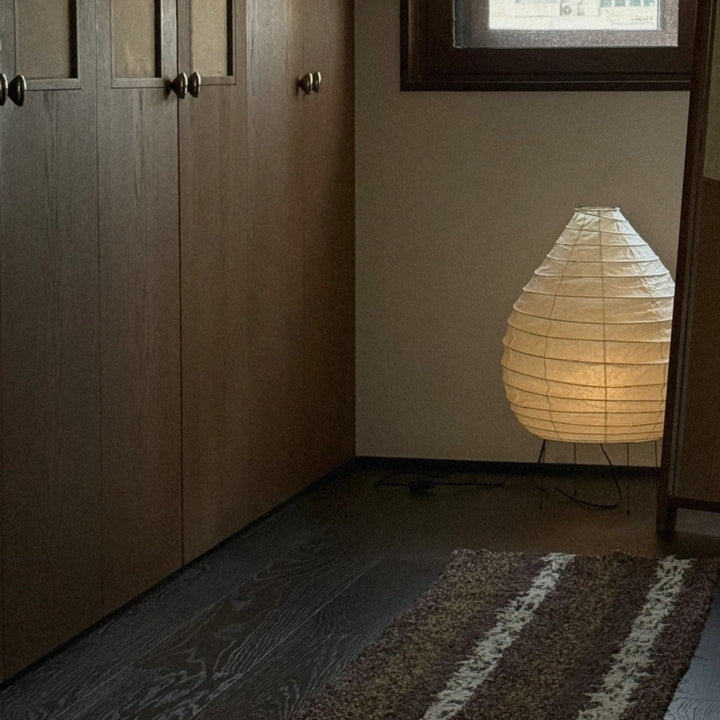 japandi style washi paper floor lamp creating warm soft lighting in a bedroom corner.