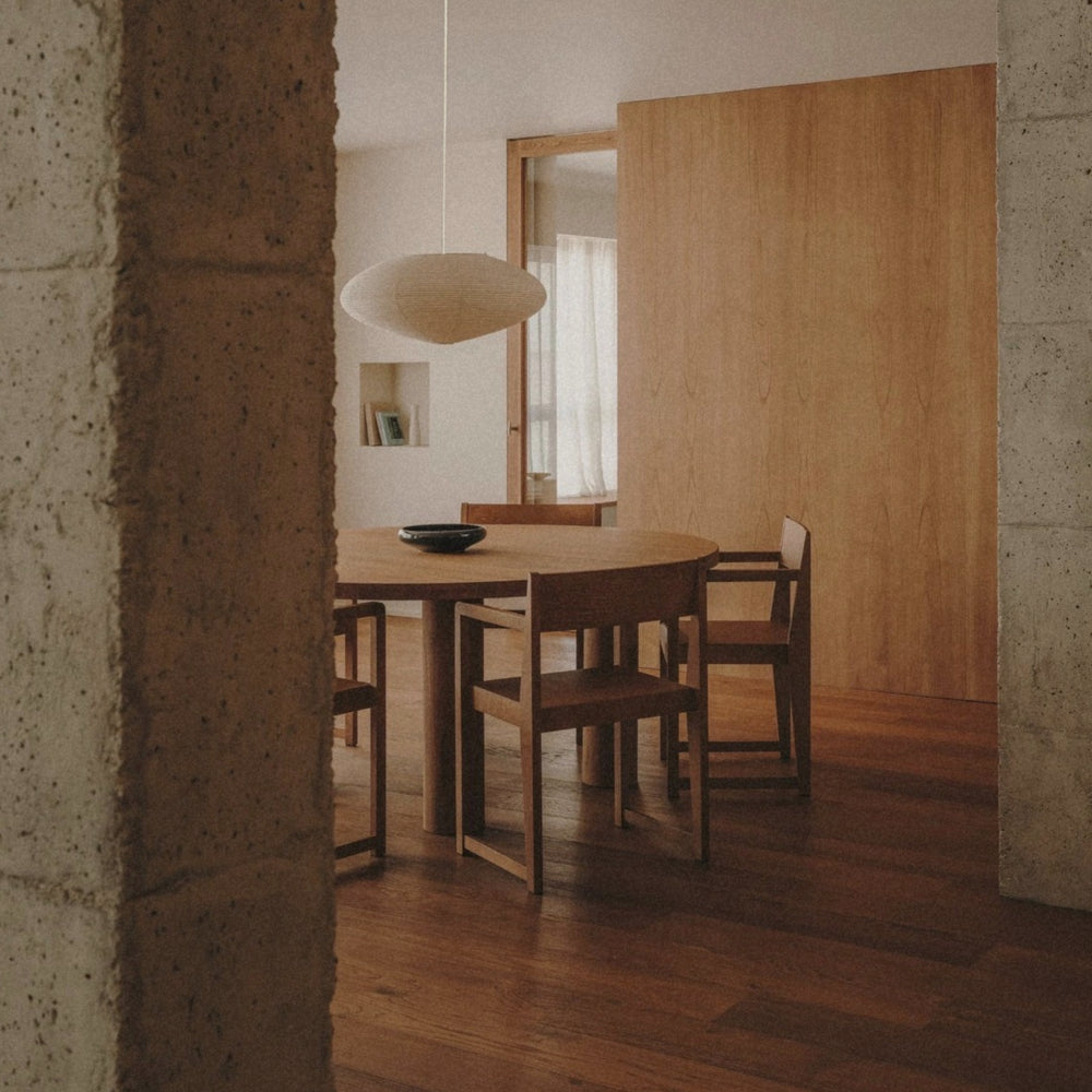 japanese paper pendant light placed over a dining table in a quiet contemporary interior.