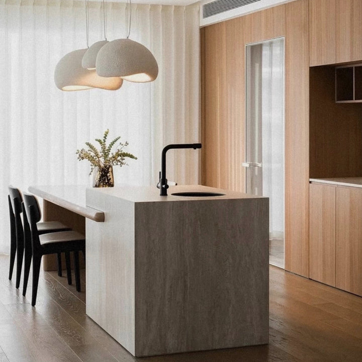pendant light positioned over a kitchen island with seating in a contemporary interior.